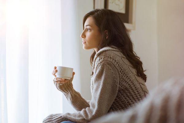 Woman sitting quietly with coffee, looking out the window — social anxiety therapy Los Angeles