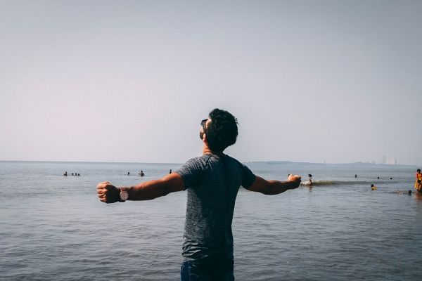 Man standing on the beach with arms outstretched toward the ocean—symbolizing personal growth through IFS therapy in Los Angeles.