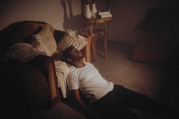 Man lying on apartment floor in Los Angeles showing signs of nervous system dysregulation from trauma