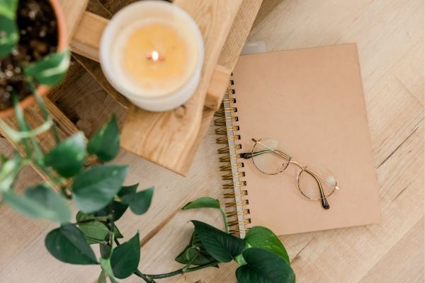 Relaxing Somatic and holistic therapy office in Los Angeles. Candle is burning, pink notebook, and glasses on table.
