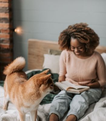 Woman reading with her dog in a cozy Los Angeles apartment, representing balance and self-care through somatic therapy in Los Angeles.
