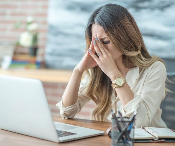 Frustrated woman at computer with hands on head — symbolizing the inner conflict IFS therapy in Los Angeles helps address