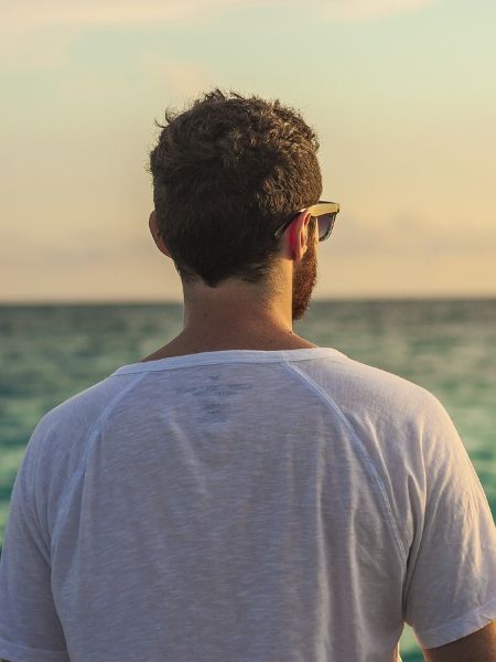 Man in a white shirt gazing at the ocean, signifying calm and emotional clarity in somatic therapy, Los Angeles.