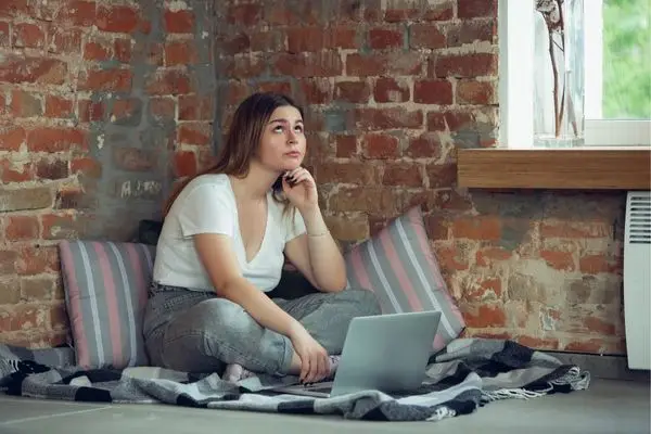 Person staring off while working on laptop, spaced out in a reflective functional freeze state