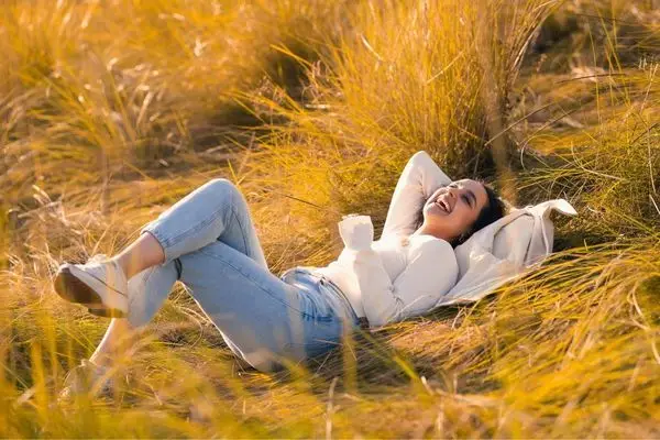 Woman relaxing in tall grass, symbolizing emotional peace after IFS therapy in Los Angeles