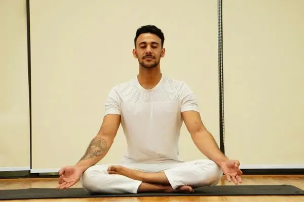 Person sitting cross-legged in meditation, practicing breath awareness for nervous system regulation.