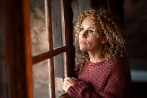 Woman sitting calmly by a sunlit window in the morning, reflecting on healing from a codependent relationship